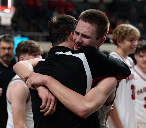 Coach embracing a basketball player after a game